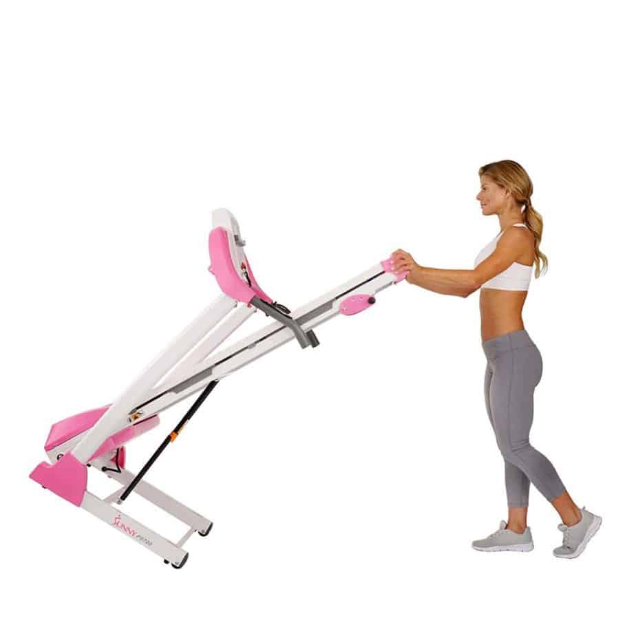 A lady is rolling the Sunny Health & Fitness P8700 Treadmill to storage